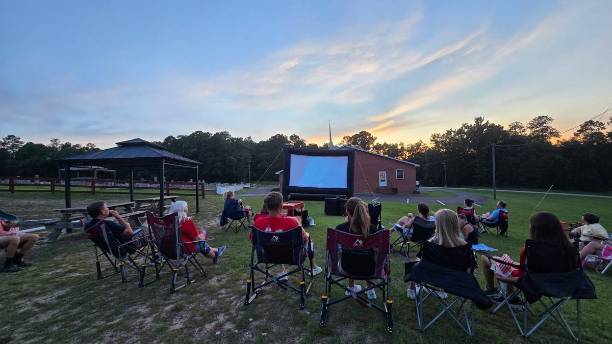 Outdoor movie night at sunset with audience seated in chairs