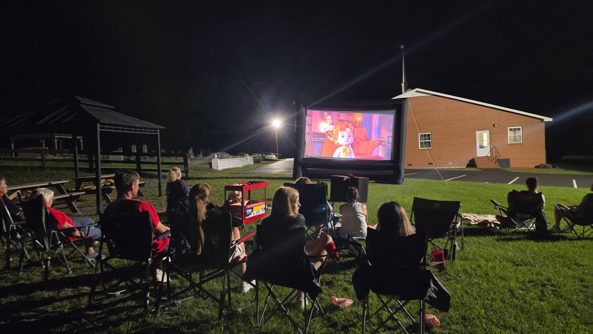 Animated movie playing on inflatable screen at night with audience